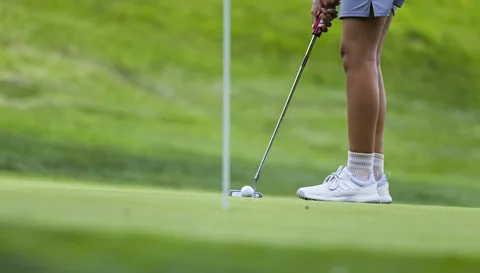A golfer’s putt rolling toward the hole