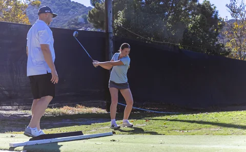 Coach Jon watches a player swing during a lesson on the range