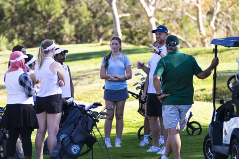 Coach Jon talks with a girls’ golf team on the course